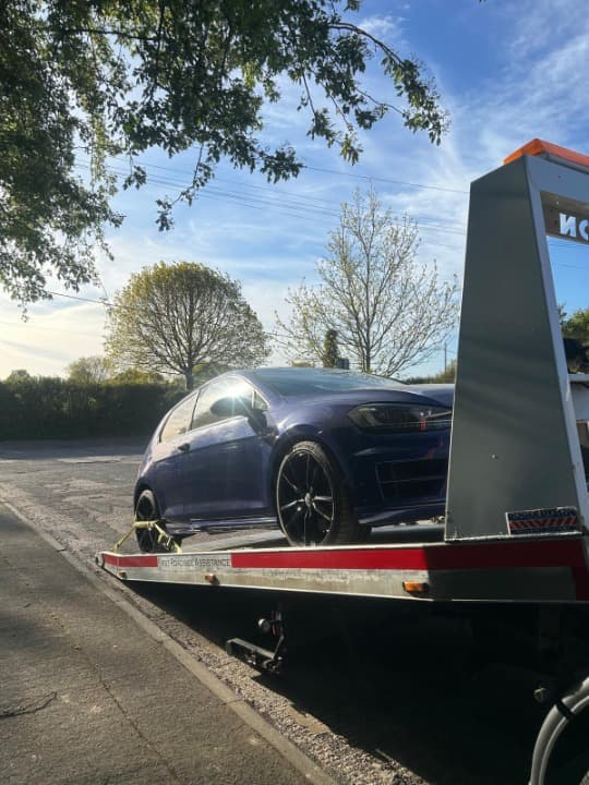 recovery truck transporting car on highway